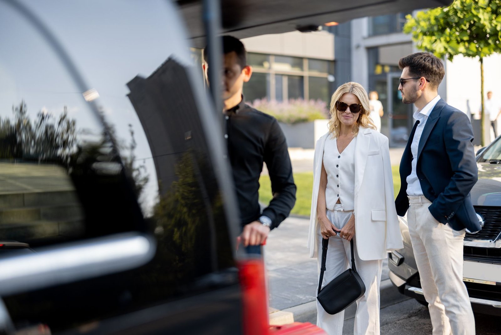 Man opens car trunk for a woman and man