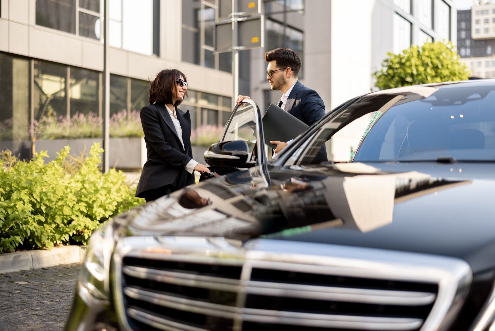 Businesspeople near a black luxury car