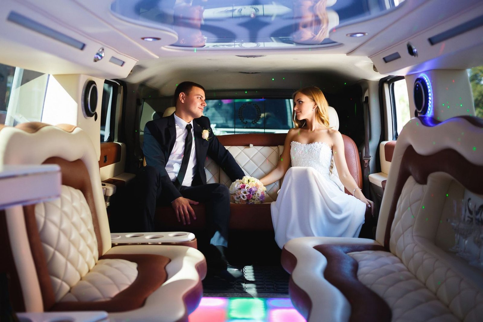 Bride and groom holding hands inside a luxury limousine